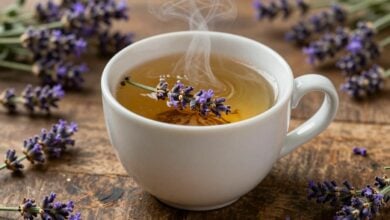 Xícara fumegante de chá de lavanda cercada por flores frescas em uma mesa de madeira rústica