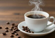 Xícara de café fumegante ao lado de grãos de café, representando o tema café e emagrecimento