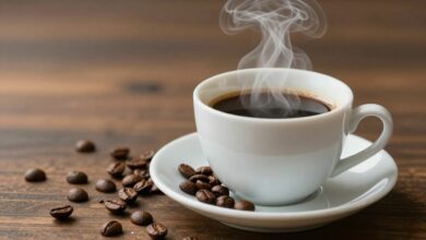 Xícara de café fumegante ao lado de grãos de café, representando o tema café e emagrecimento