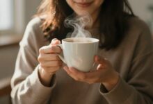 Pessoa apreciando uma xícara de café ao raiar do dia em um ambiente acolhedor