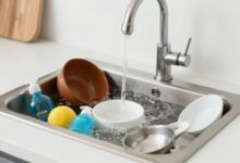 Uma pia de cozinha com acúmulo de água e utensílios de limpeza ao lado
