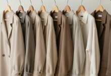 Uma mulher sorrindo enquanto organiza cuidadosamente seu guarda-roupa minimalista com peças de roupas de alta qualidade em tons neutros, simbolizando o conceito de slow fashion.