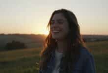 Uma pessoa sorrindo, em paz, em um belo cenário de natureza ao pôr do sol, simbolizando a felicidade e a qualidade de vida.