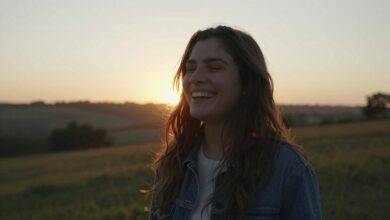 Uma pessoa sorrindo, em paz, em um belo cenário de natureza ao pôr do sol, simbolizando a felicidade e a qualidade de vida.