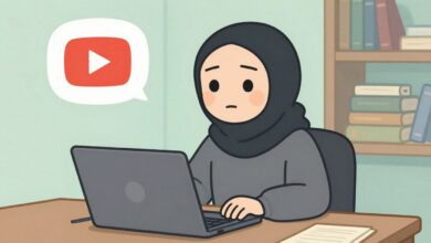 Uma figura encapuzada e anônima sentada em frente a um computador com o símbolo do YouTube brilhando na tela, representando o conceito de um canal dark.