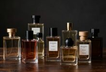 Uma coleção elegante de frascos de perfumes masculinos de diferentes formatos e cores, dispostos sobre uma superfície de madeira escura com um fundo sofisticado e sombrio.