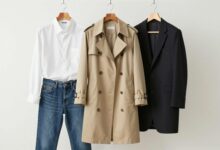 Um guarda-roupa cápsula elegantemente organizado com peças clássicas como um trench coat bege, uma camisa branca, jeans de corte reto e um blazer preto, em um ambiente minimalista e iluminado.