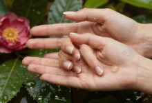Uma imagem elegante mostrando mãos bem cuidadas com unhas saudáveis e brilhantes, com elementos naturais como flores ou gotas de água ao fundo, simbolizando saúde e hidratação.