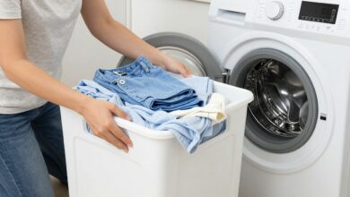 Uma pessoa sorrindo enquanto organiza roupas coloridas e brancas em cestos de lavanderia, com uma máquina de lavar moderna ao fundo, ilustrando a organização para a lavagem de roupas.