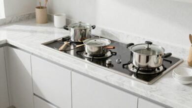 Uma cozinha moderna e impecavelmente limpa, com bancadas de mármore brilhando, armários brancos e utensílios de aço inoxidável organizados, banhada por uma luz natural suave.
