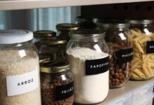 Despensa doméstica organizada com potes transparentes bem vedados contendo arroz, feijão, farinha, massas e castanhas, em ambiente seco e protegido da luz.